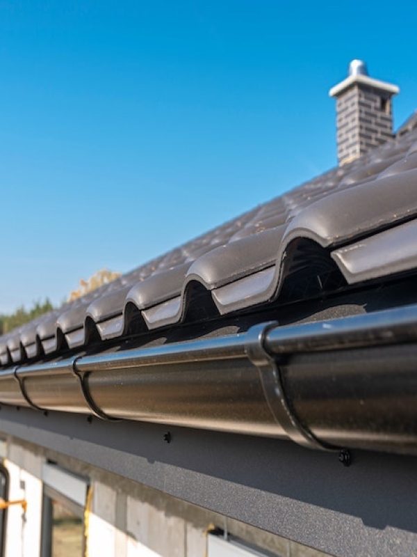 a-metal-black-gutter-on-a-roof-covered-with-ceramic-tiles-close-up-shot-